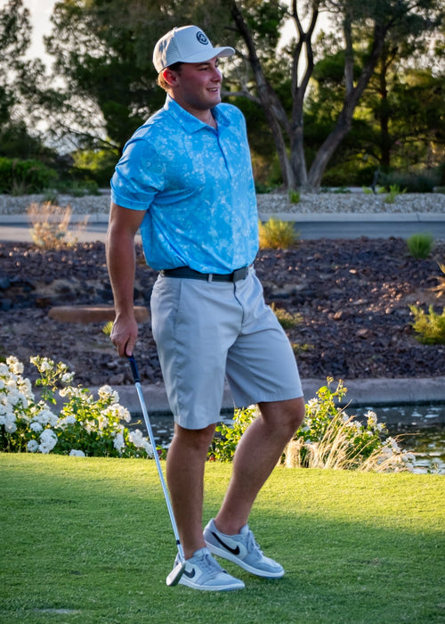 Man playing golf on a green course with trees and flowers in the background
