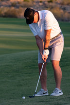 Golfer taking a swing on a golf course with trees in the background