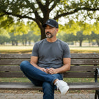 Man wearing a black Scooter Martini performance cap with laser-perforated panels while sitting on a park bench.